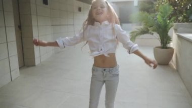 Junior girl dancing against blurred architecture background
