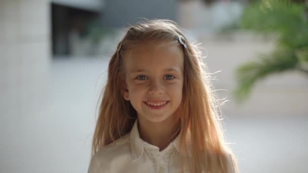 Chica adolescente sonriendo amplia, de pie contra el fondo de la arquitectura — Vídeos de Stock