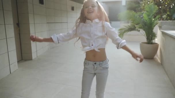 Junior girl dancing against blurred architecture background — Stock Video