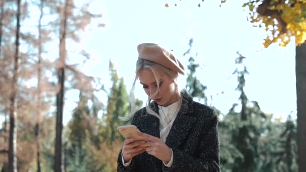 Junges erwachsenes Mädchen ruht sich tagsüber mit Smartphone im Park aus — Stockvideo