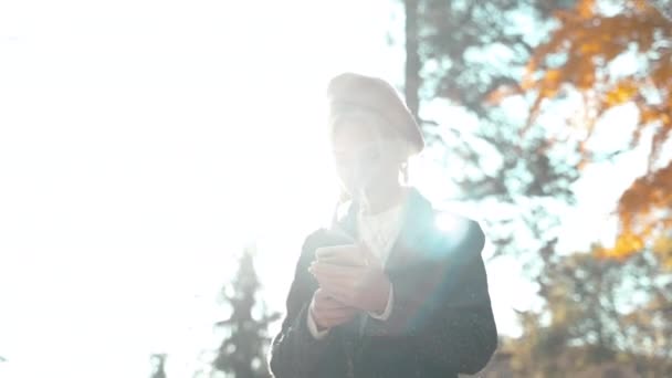 Νεαρή ενήλικη γυναίκα που περνά το φθινόπωρο ημέρα του Σαββατοκύριακου σε εξωτερικούς χώρους με smartphone — Αρχείο Βίντεο