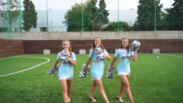 Jovens meninas em cheerleader em uniforme com pom poms apoiar equipe esportiva na faculdade — Vídeo de Stock