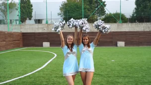 Cheerleaders girls in uniform with pom poms standing together, support high school sport team — Αρχείο Βίντεο