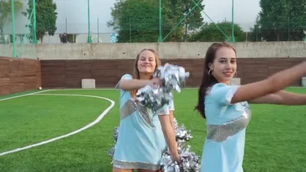 Sportiga cheer ledare flickor i uniform med pom poms stödja gymnasiet idrottslag — Stockvideo