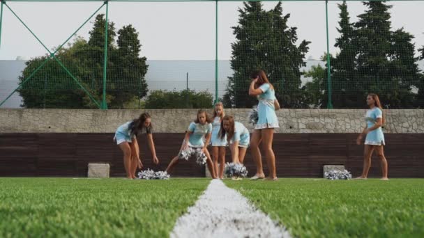 Cheer leaders teenage girls in uniform with pom poms training support high school sport team — Stock Video