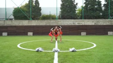 Teenage girls in cheerleaders in uniform making acrobatic figure together