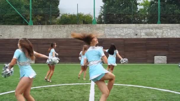 Adolescentes en porristas en uniforme con pompones apoyan al equipo deportivo en la universidad — Vídeos de Stock