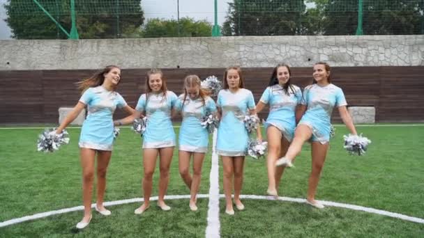 Jovens meninas em cheerleader em uniforme com pom poms fazendo movimentos de ginástica juntos — Vídeo de Stock