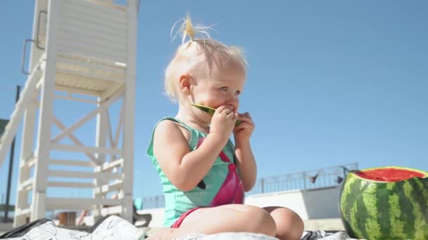 Liten flicka som sitter nära vattenmelon och äter frukt i 4k — Stockvideo