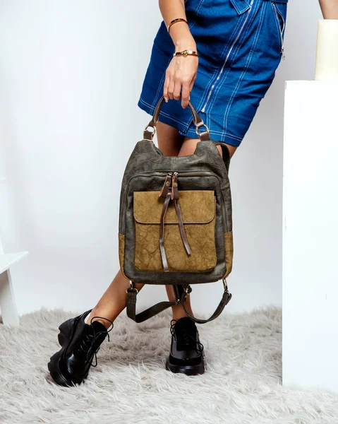 woman holding khaki leather backpack