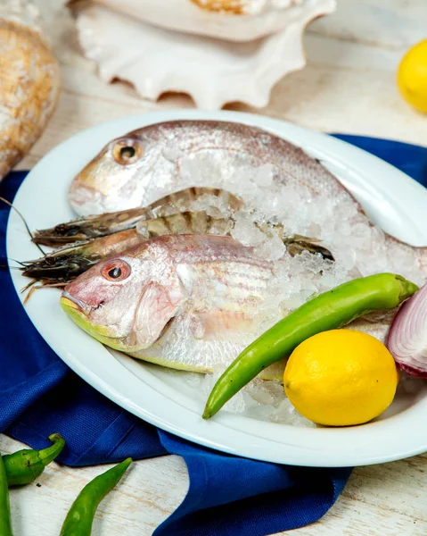 Fresh fish and prawns in ice garnished with pepper, lemon — Stock Photo, Image