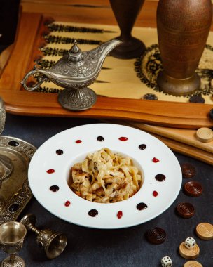 Tavlanın yanında servis edilen tavuklu fettuccini tabağı.