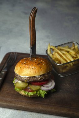 Salatalık, soğan, marul ve domatesli küçük sığır etli burger.