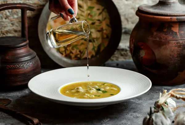 Женщина наливает уксус в суп из клецок Душбары — стоковое фото