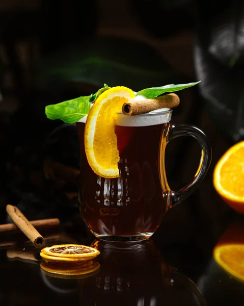 Beverage topped with orange slice cinnamon and leaves — Stock Photo, Image
