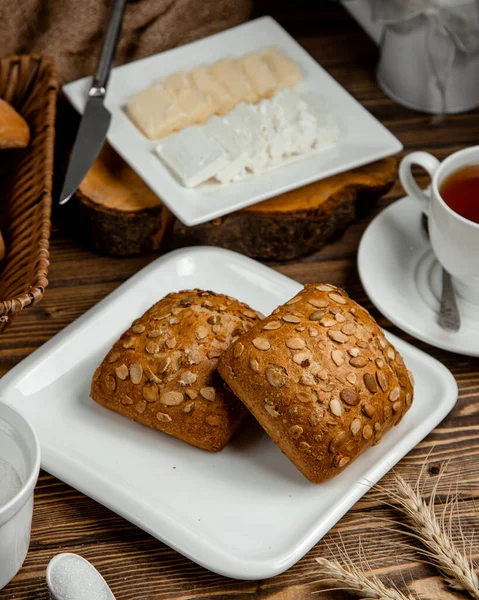 Черный хлеб, покрытый семенами, тарелка нарезанного сыра — стоковое фото
