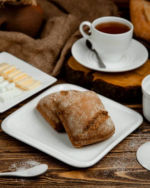 Белая тарелка хлеба и чашка горячего чая — стоковое фото