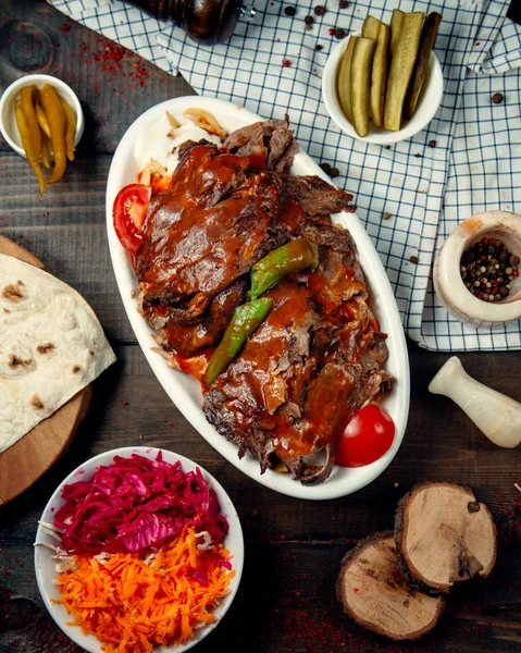 İskender kebabının üst manzarası domates sosuyla süslenmiş.