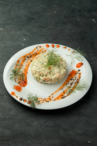 Σαλάτα olivier σε πιάτο διακοσμημένο με σάλτσα και άνηθο — Φωτογραφία Αρχείου