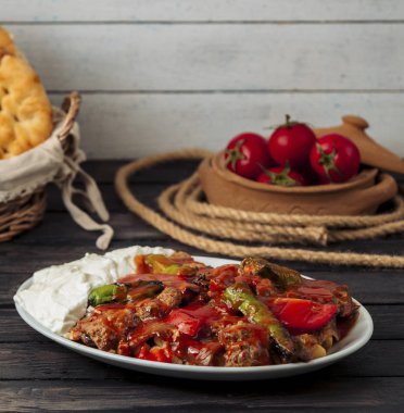 İskender kebabı domates sosuyla süslenmiş, yoğurtla servis edilmiş.