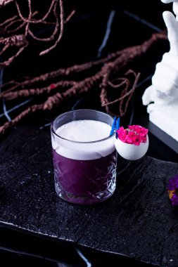 Yumurta kabuğuyla süslenmiş, kristal bir bardak mor kokteyl.