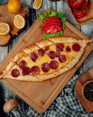 Masasında sosis olan Türk pidesi.