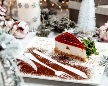 Üstünde kırmızı jöle olan peynirli pasta.