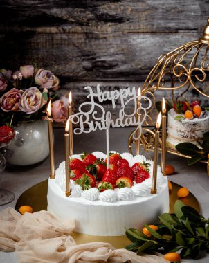 Çilekli doğum günü pastası altın mumlar ve mutlu yıllar standı