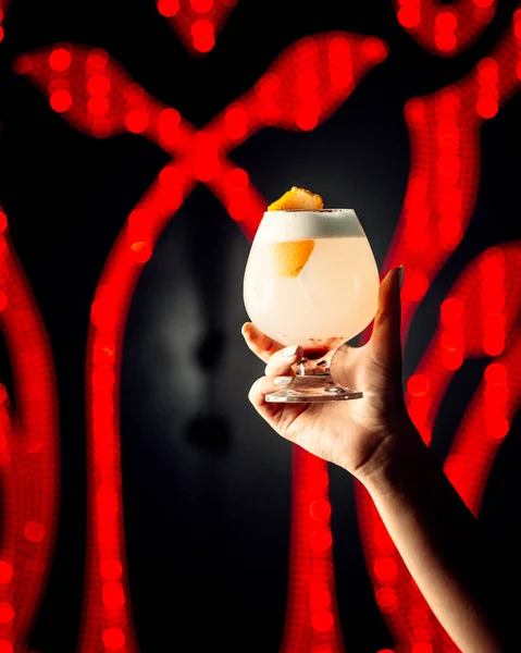 Woman hands holds a glass of cocktail with orange zest — Stock Photo, Image