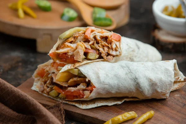 Domatesli düz ekmeğe sarılmış tavuk kebabı, salatalık turşusu.