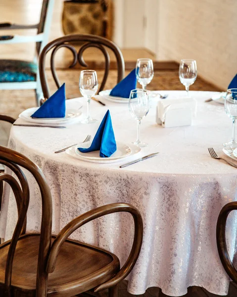 Mesa de restaurante con mantel de encaje blanco y servilletas azules — Foto de Stock