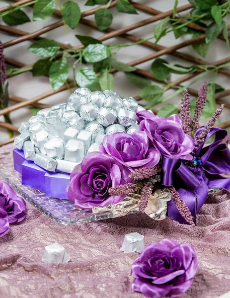 Schokoladenhoncha bedeckt mit silbernen und lila Wraps, dekoriert mit lila Blumen — Stockfoto