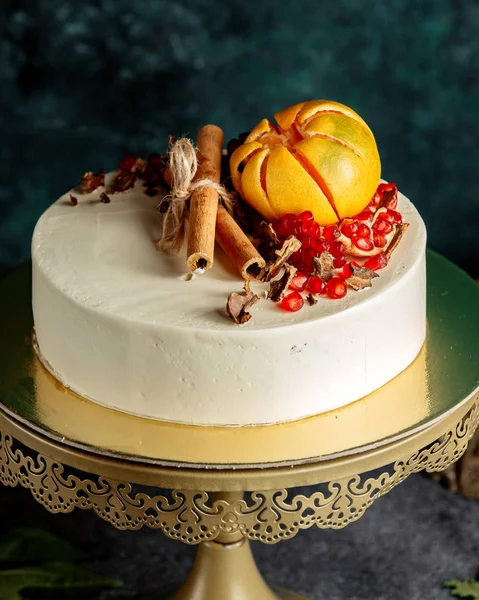 白いクリームとザクロ、グレープフルーツとシナモンスティックで覆われたケーキ — ストック写真