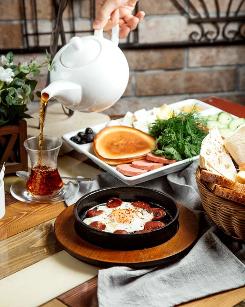 Breakfast setup with egg with sausages pancake herbs cheese vegetables and tea — Stock Photo, Image