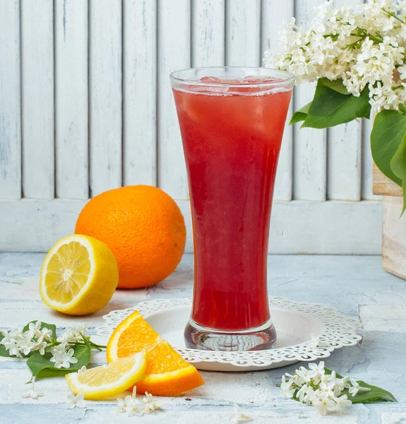 Narancs és citromlé magas üvegben, jégkockákkal, világos háttérrel — Stock Fotó