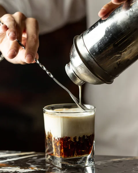 바텐더는 숟가락을 사용하여 아이스 커피에 크림을 붓는다 — 스톡 사진
