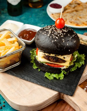 Salatalık ve domatesli siyah sığır etli burger.