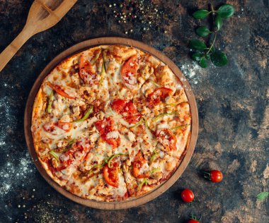 Doldurulmuş biberli tavuk pizza, domates, ahşap tahtada peynir.