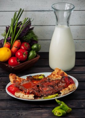 Domates sosuyla süslenmiş iskende kebabı. Domates, biber ve ekmekle servis edilmiş.