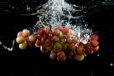 Üzüm kümesi siyah arkaplanda suya sıçradı