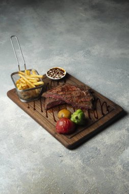 Yanında patates kızartması ve sebzeli orta pişmemiş biftek.