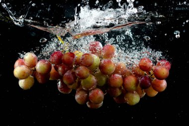 Üzüm siyah arkaplanda suya sıçrıyor