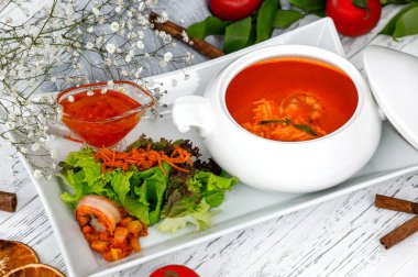 Salatayla servis edilen seramik tabakta servis edilen baharatlı karides çorbası.