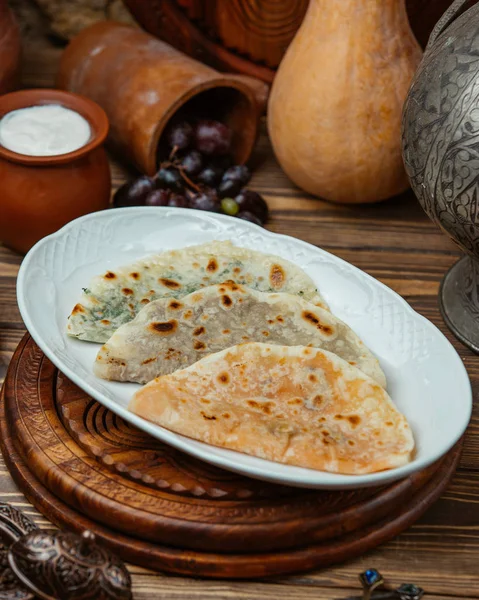 Mixed gutab meat-stuffed flatbread in platter with yoghurt in pot — Stock Photo, Image