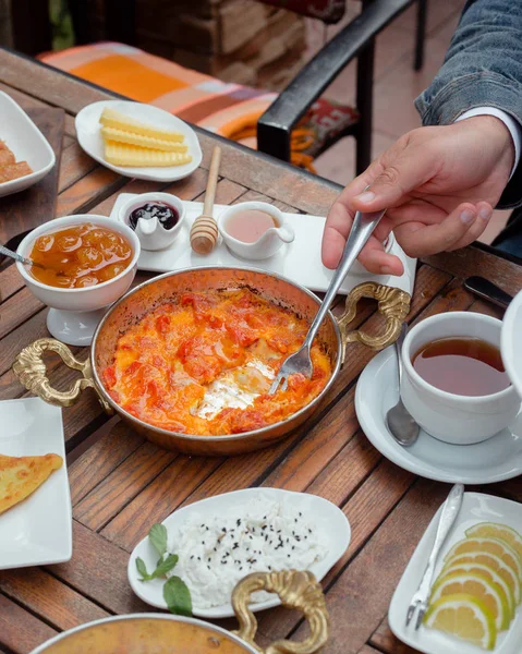 Человек, принимающий помидоры и яйца блюдо с вилкой на традиционном завтраке — стоковое фото