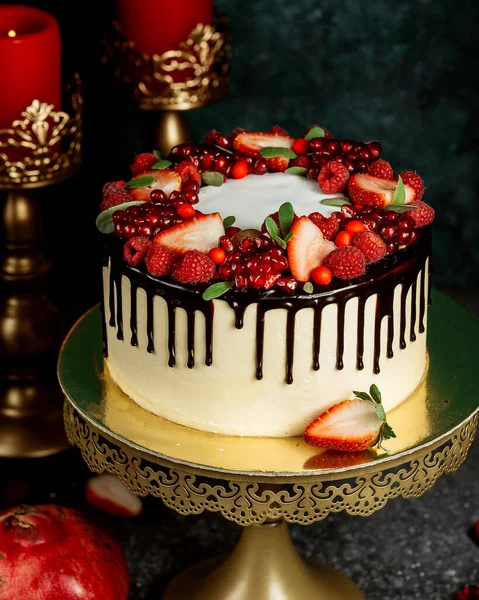 chocolate drip cake with white cake garnished with berries