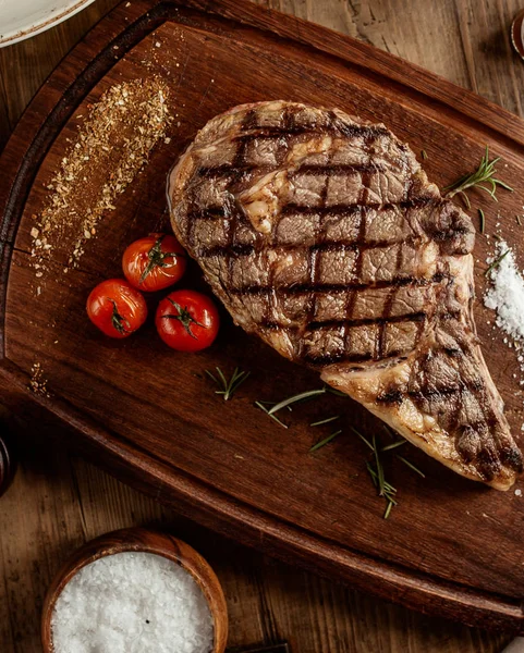 Draufsicht auf Rindersteak mit Salzkräutern und Kirschtomaten an Bord — Stockfoto