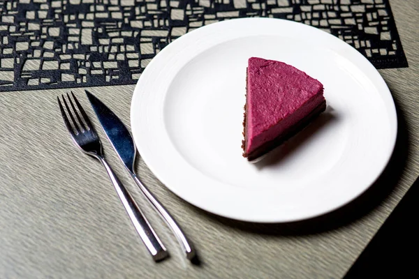 ホワイトプレートのラズベリーチーズケーキをテーブルの上に置いて — ストック写真
