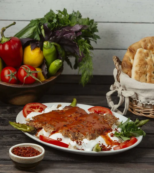 İskender kebabı domates sosuyla süslenmiş yoğurt.