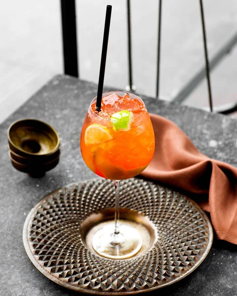 Ένα ποτήρι κρύο πορτοκαλί κοκτέιλ σερβίρεται σε όμορφο χάλκινο πιάτο — Φωτογραφία Αρχείου